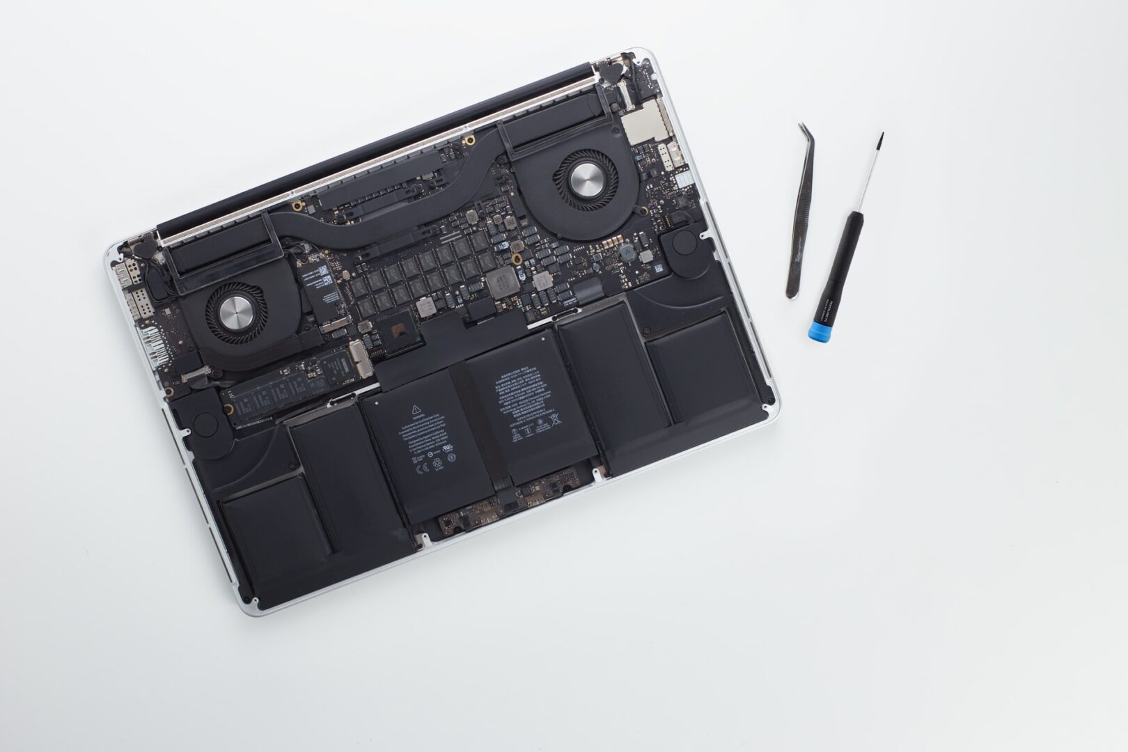 An opened MacBook with repair tools beside it
